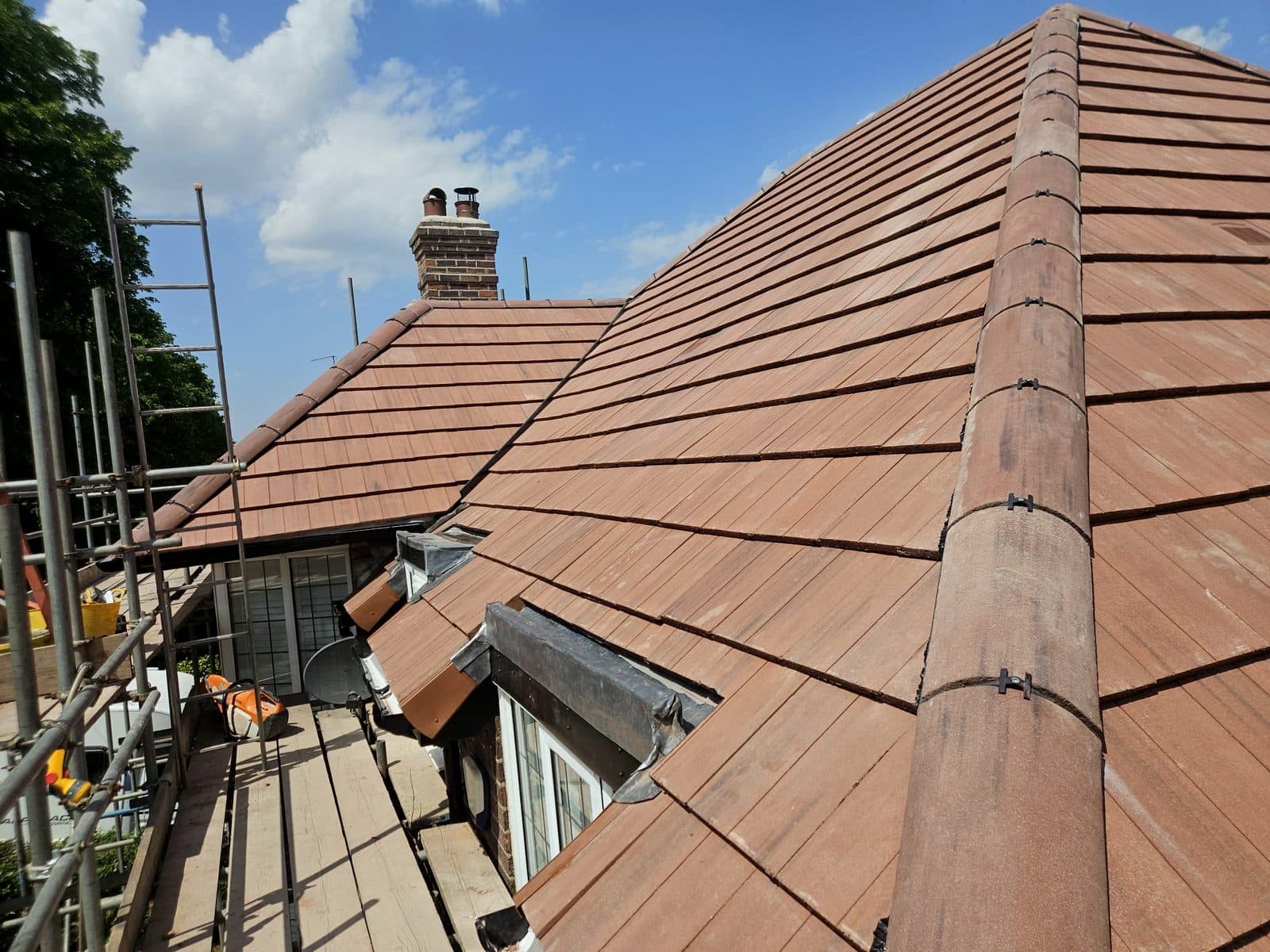 A finished brown plain tile hip roof on a dormer bungalow, with new lead to the dormer and the ridge clipped down