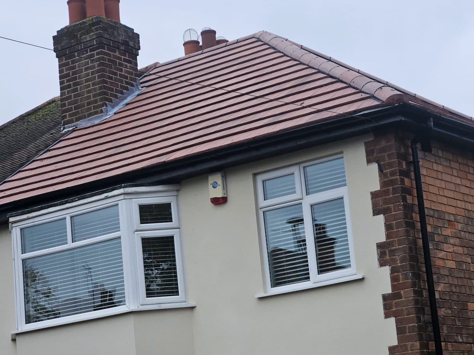 A finished plain tile hip roof on a rendered house, with new lead flashing around the chimney