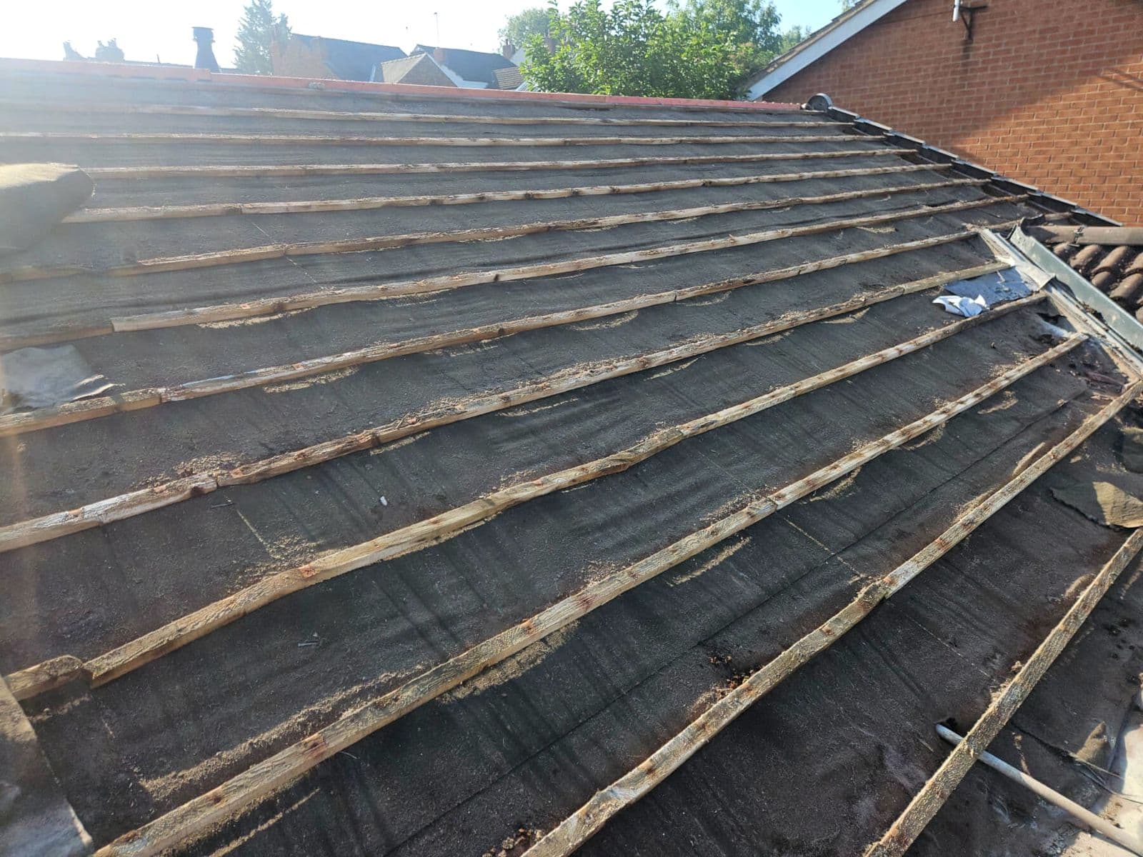 A roof stripped back to the old battens before the new covering goes on