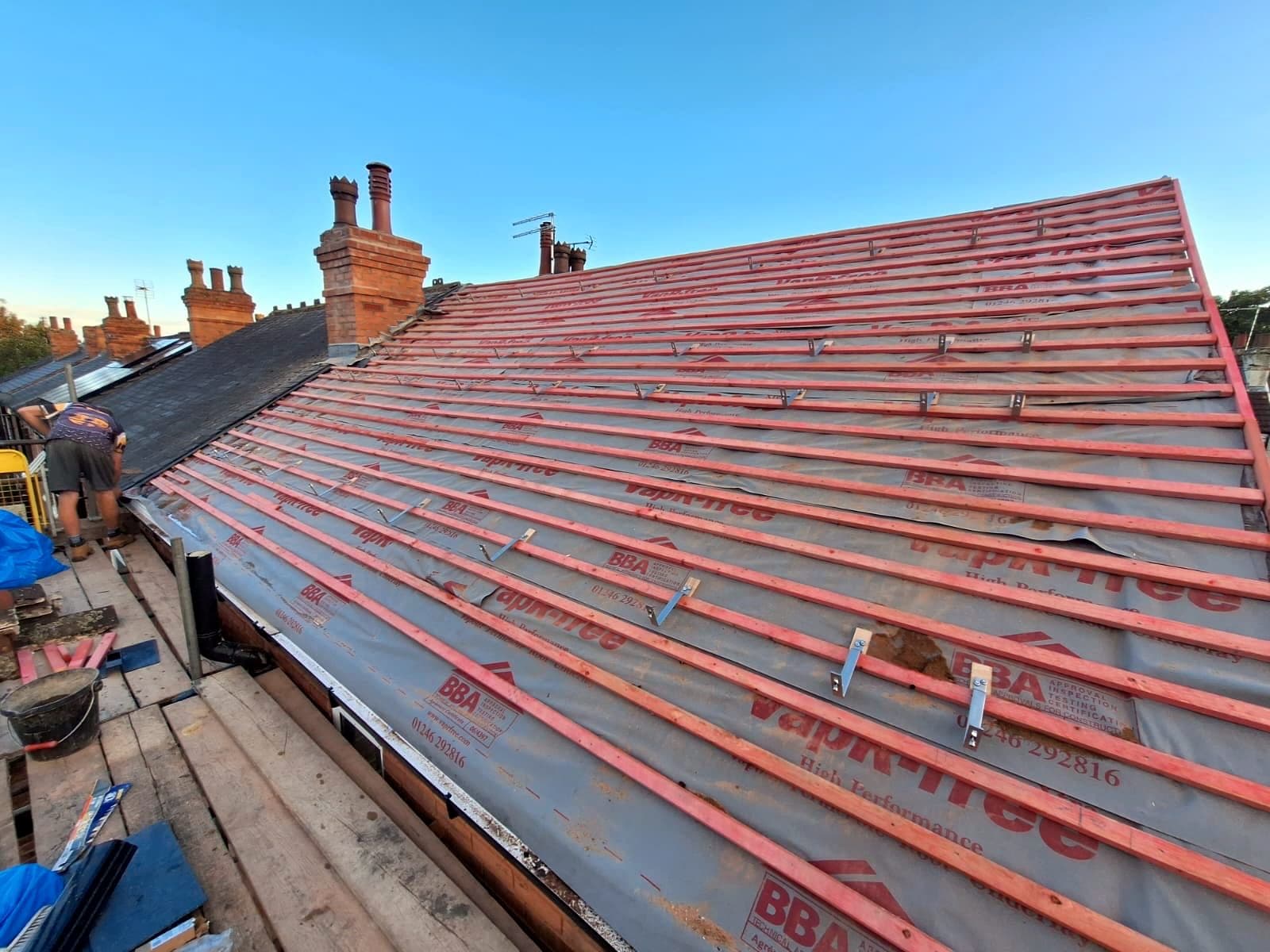 New breathable membrane and battens going on over a Nottingham terrace, chimney stacks behind
