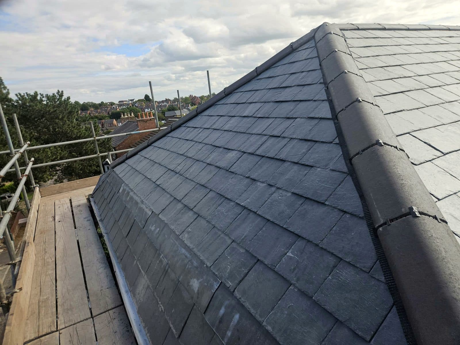 New slate hips and a clipped-down ridge, looking out over Nottingham from the scaffold