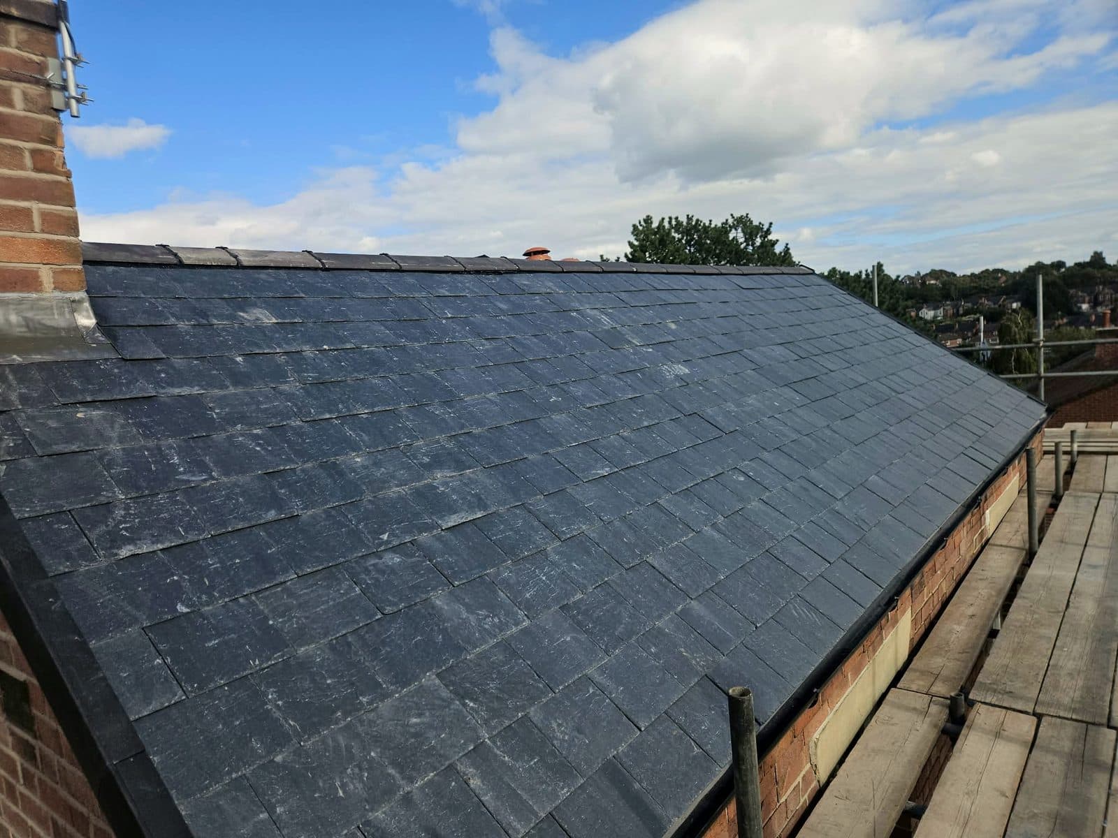 The finished natural slate roof in Thorneywood under a blue sky, with new lead around the chimney