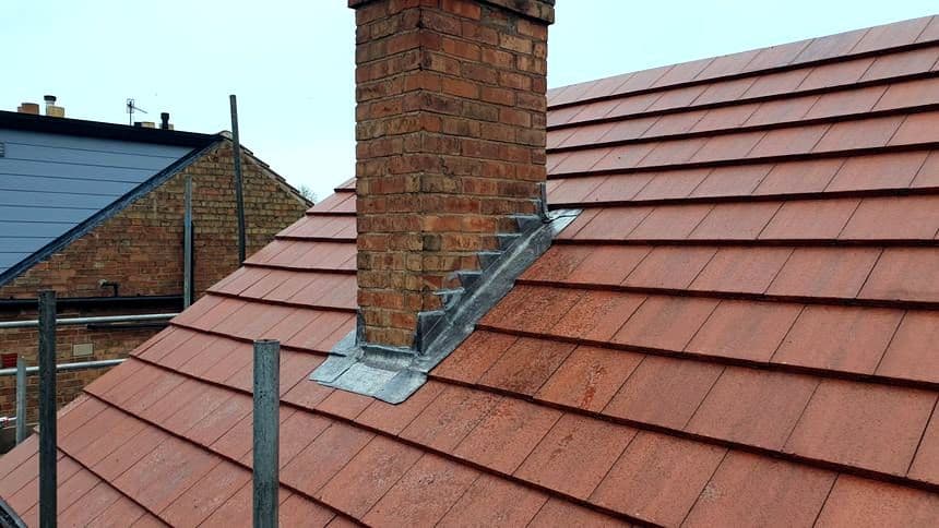 New lead flashing dressed around a brick chimney stack on a red tile roof