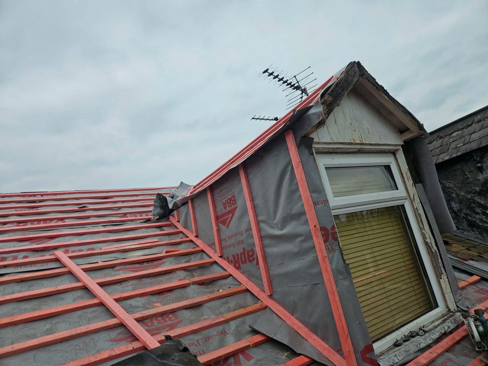 A dormer roof stripped, with new red membrane and battens on