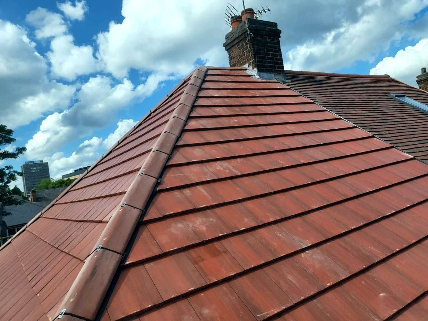 The finished red clay tile roof photographed along the hip, with the Nottingham skyline behind