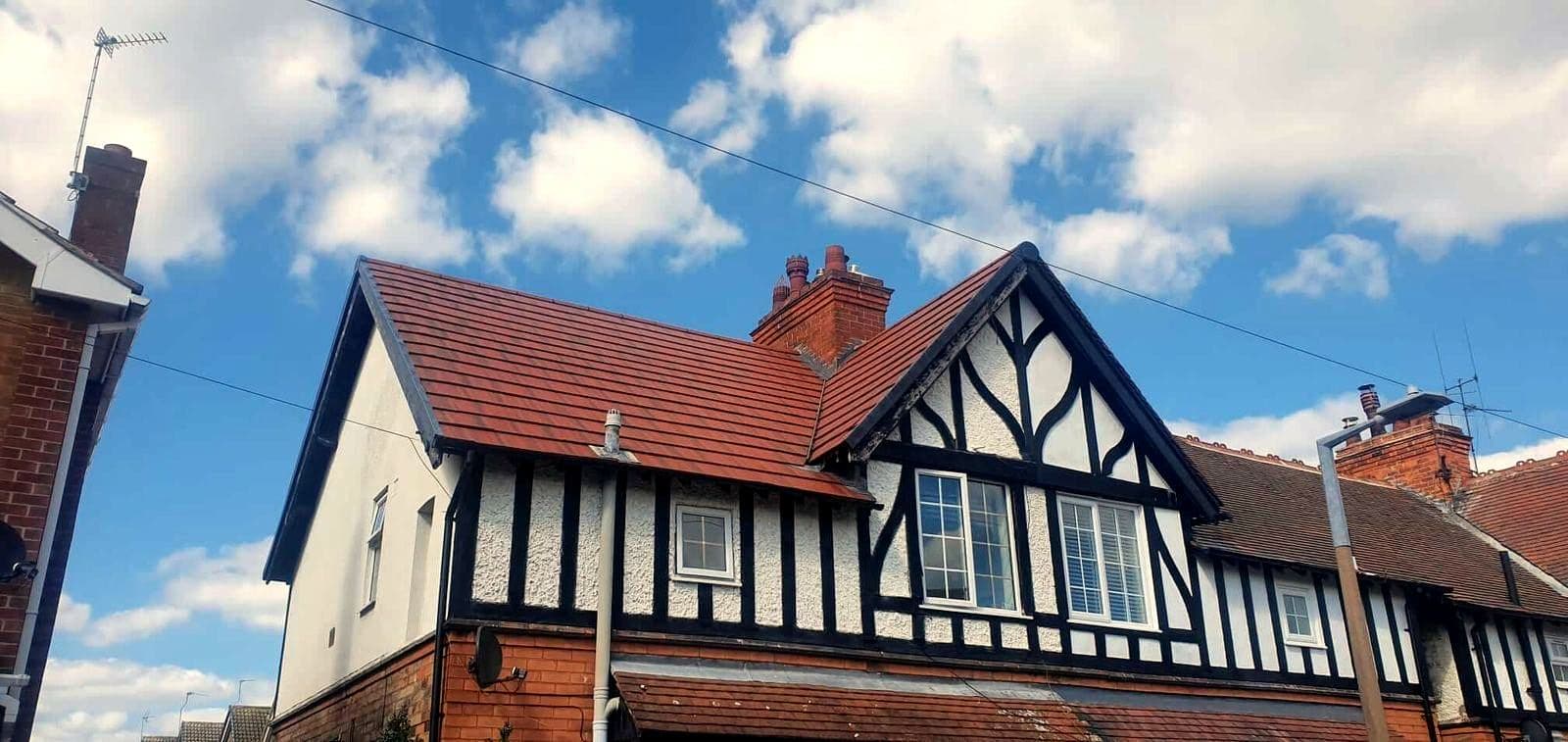 A newly tiled red clay gable roof on a black and white Tudor style house in Nottingham