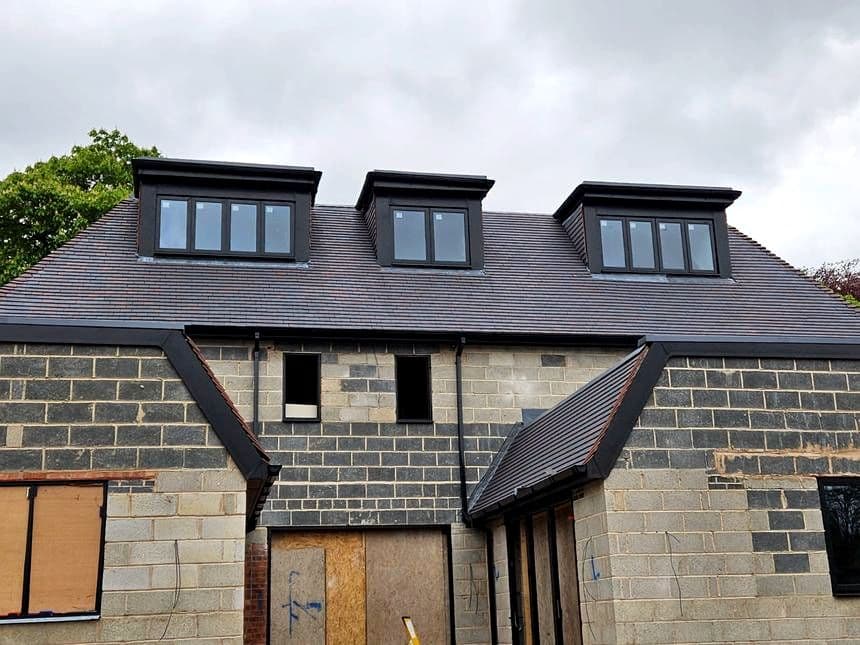 Three new dormer roofs on a new build house in grey tile