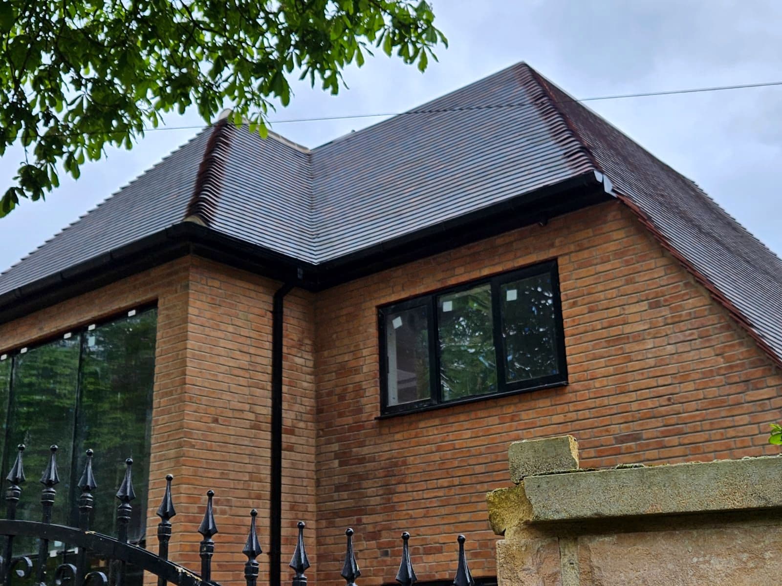 The grey tiled roof and dormers on the brick new build