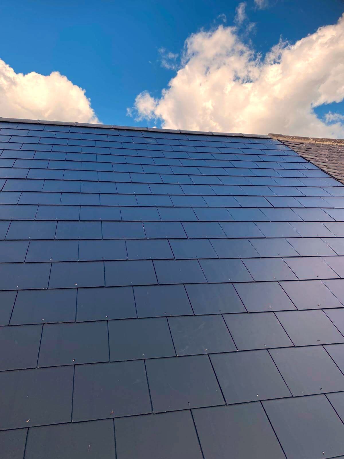 A finished natural slate roof against a blue sky