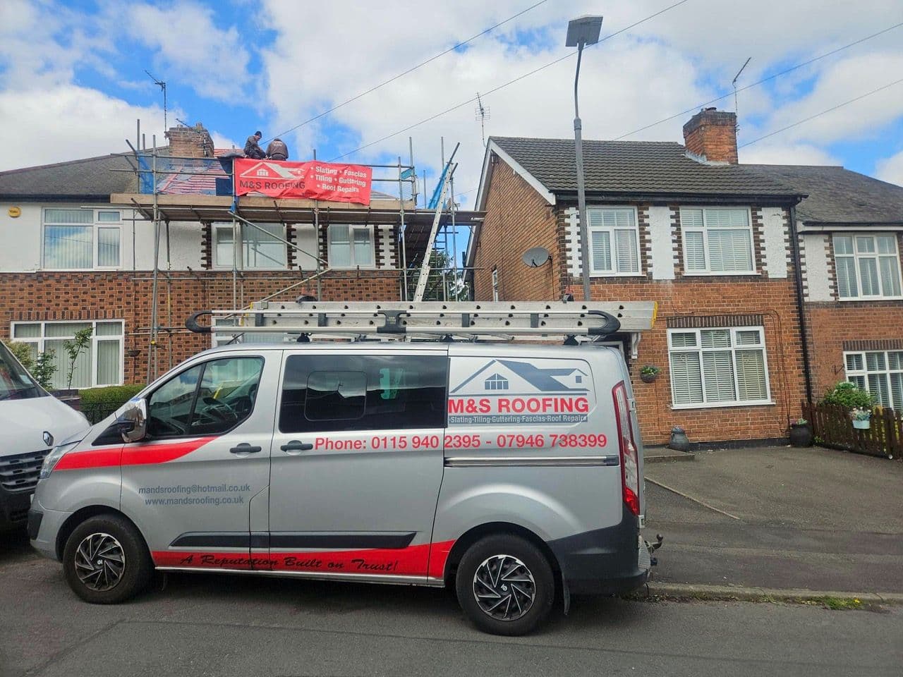 An M&S Roofing van outside a scaffolded semi-detached house